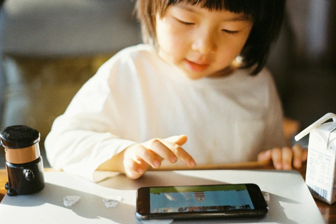 girl in white long sleeve shirt holding black smartphone